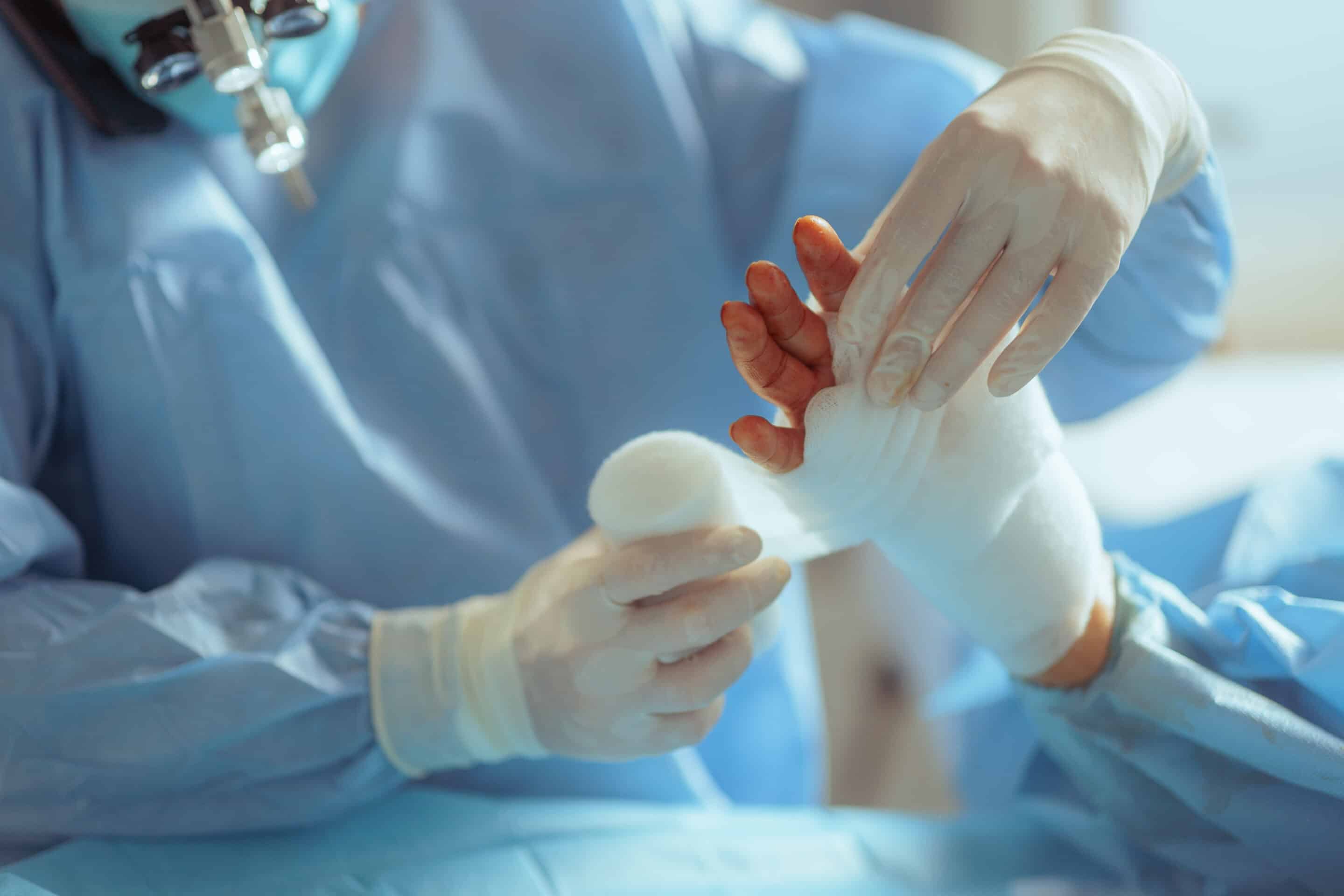 Surgeon Applying a Bandage in Postoperative Procedure. Doctor giving post operator assistance to patient